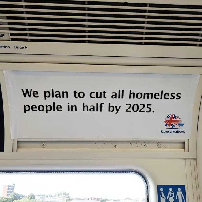 En skylt på ett tåg med texten "We plan to cut all homeless people in half by 2025".