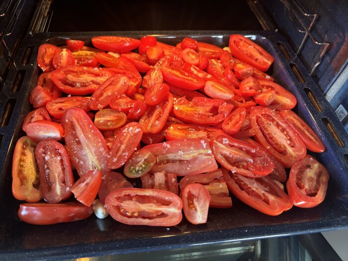 Skivad San Marzano-tomater med salt och kryddor ligger på en bakplåt redo att rostas i ugnen för att göra tomatsås.