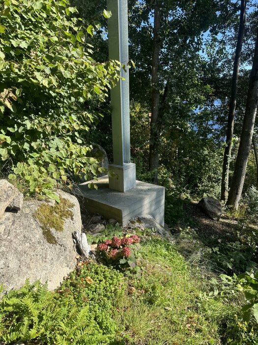 Galvad stödmur och plintar omgivna av grönska och natur, med stenar och växtlighet i en kuperad terräng.