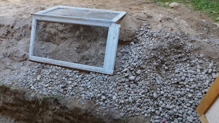 Såll med glasrutor används för att separera jord och grus på en byggarbetsplats vid en grundläggningsrenovering.