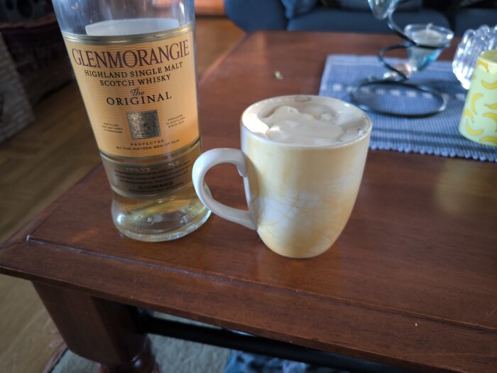 En flaska Glenmorangie whisky och en mugg med Irish Coffee på ett träbord.