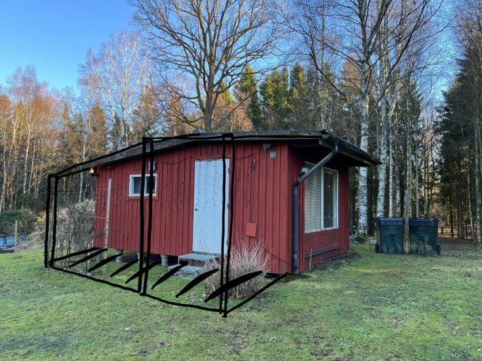 Röd stuga med vit dörr fotograferad från höger sida; svarta markeringar visar planerat utbyggnadsområde för terrass med tak. Skog i bakgrunden.