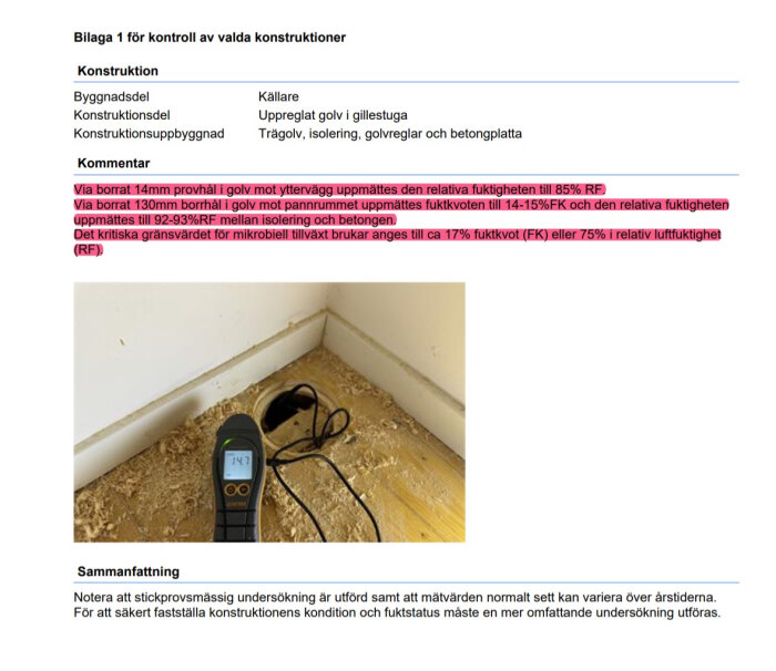 Fuktmätare som visar 14,7% bredvid ett borrhål i golvet i en källare, med sågspån och kablar runt om.