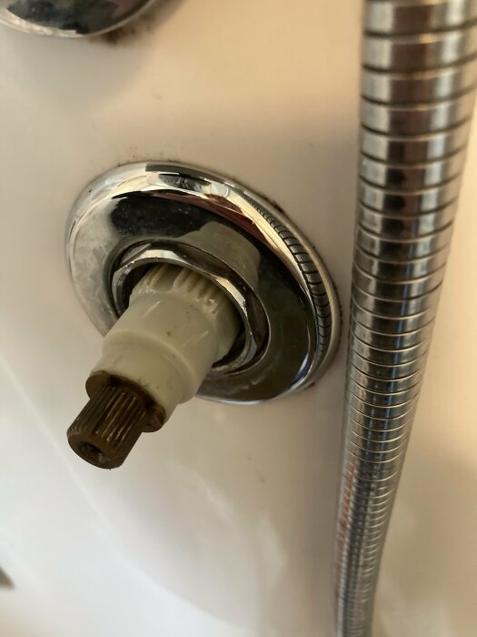 Närbild av en termostat i en ångdusch med en fastskruvad mutter bredvid en metallslang.