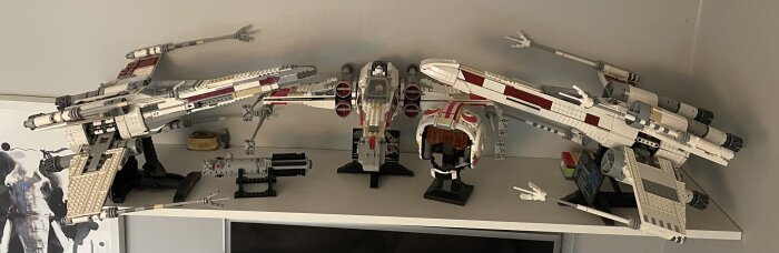 Modeller av tre rymdskepp byggda av Lego, och en Lego-modell av en hjälm från Star Wars, utställda på en hylla.