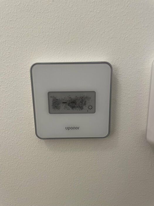 Uponor rumstermostat med utbytt display på väggen.