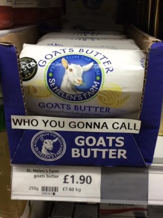 Förpackningar från St. Helen's Farm getsmör i blå kartong med texten "WHO YOU GONNA CALL GOATS BUTTER" på hylla i en butik. Priset är £1.90 för 250g.