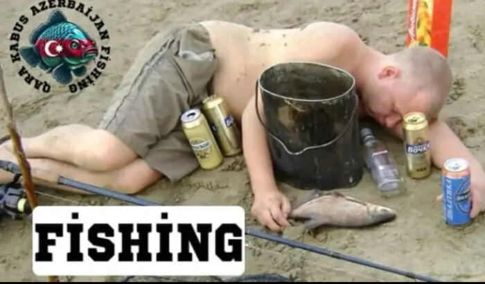 En person sover på marken vid en strand, omgiven av fisk och ölburkar. En fiskehink står bredvid personen. Ordet "FISHING" syns i bilden.