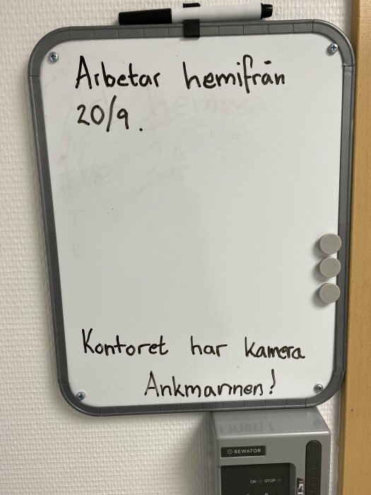 Whiteboard med texten "Arbetar hemifrån 20/9. Kontoret har kamera. Ankmannen!" och fyra runda magneter vid sidan.