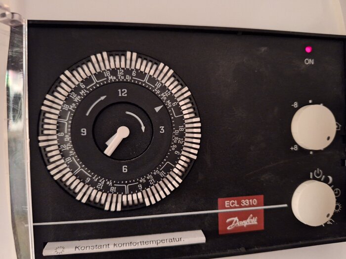 Närbild på en Danfoss ECL 3310 reglercentral för fjärrvärme med vred och rattar för temperaturinställningar.