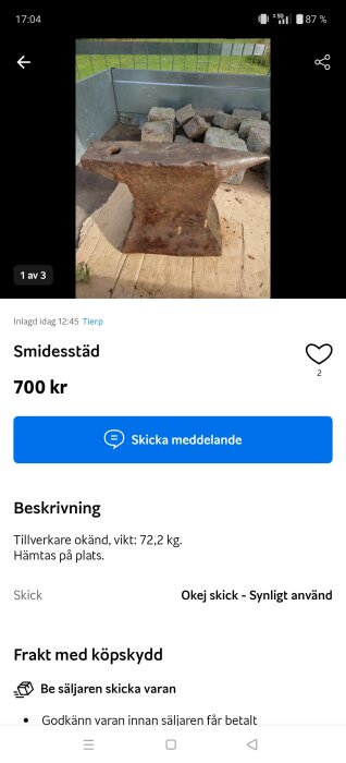 Ett stor och robust smidesstäd i metall, stående på en träunderlag, omringad av flera små stenar.