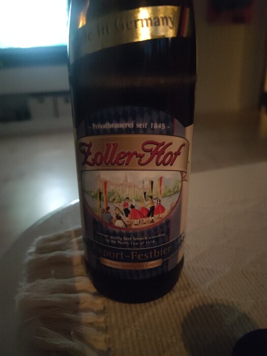 En flaska Zoller-Hof Export-Festbier, en tysk öl med en etikett som avbildar traditionellt klädda människor som firar.