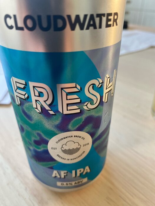 Närbild på en blå och grön burk med texten "CLOUDWATER FRESH AF IPA 0.5% ABV".