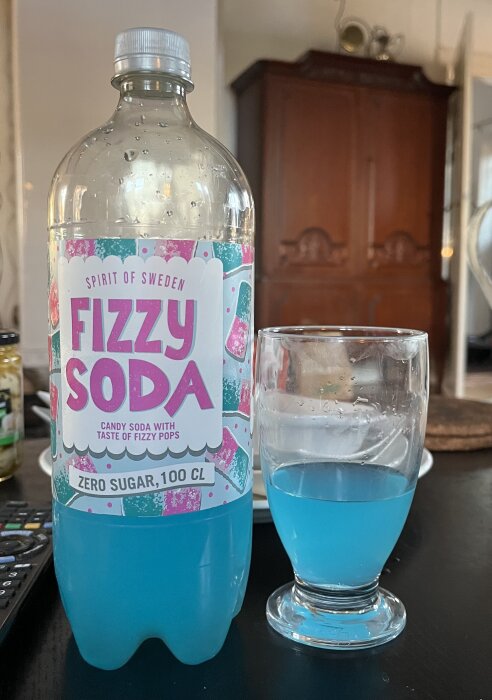 Blå läsk, "Fizzy Soda," i en flaska och ett glas, placerade på ett bord inför en tapas-kväll.