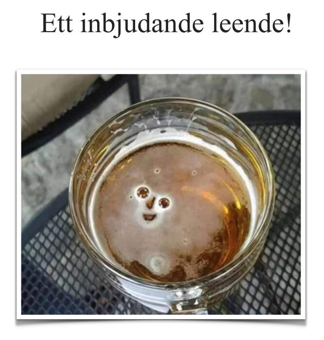 Mugg med öl på ett bord, där skum och bubblor bildar ett ansikte som ler.