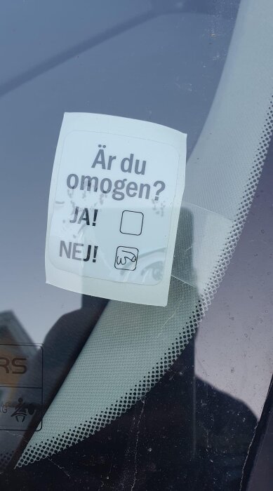 En lapp på en bilruta med texten "Är du omogen?" och två svarsalternativ: "JA!" och "NEJ!" där nej-rutan är ifylld med en tecknat snopp.