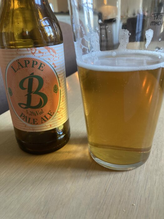 Flaska och glas med Läppe B Pale Ale på ett träbord.