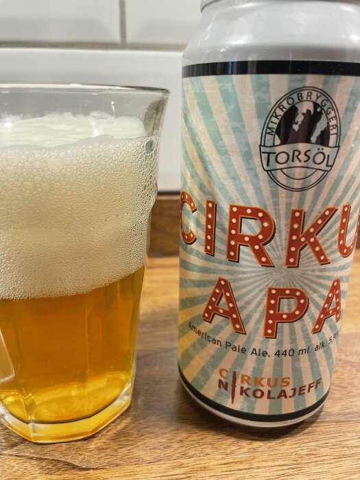 Bild på ett glas fyllt med öl bredvid en burk med etiketten "Cirkus APA" från mikrobryggeriet Torsöl.