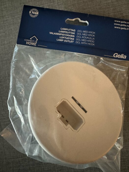 Förpackning med DCL lamputtag från Gelia, märkt "Lamp outlet DCL with hook", liggandes på en bordsyta.