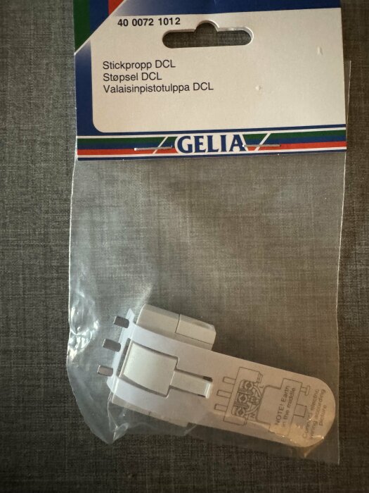Förpackning med en vit DCL-stickpropp från märket Gelia, hängande på en displaykrok.