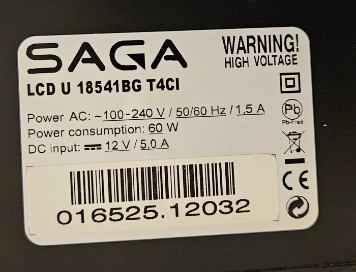Närbild på etikett från en Saga LCD U 18541BG T4CI med specifikationer om ingångsspänning, strömförbrukning, och säkerhetsvarningar.