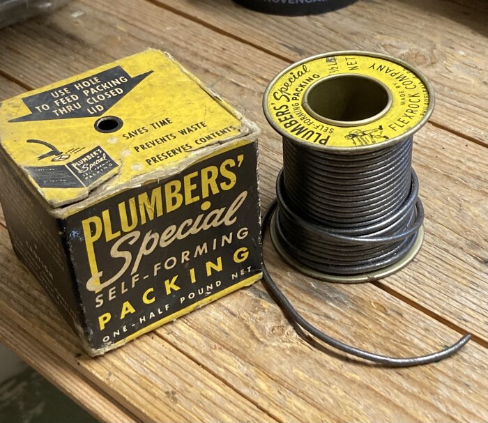 En rulle med svart packningsmaterial och en guldfärgad textil med ordet "PLUMBERS' Special." En gul rektangel till höger visar "SELF-FORMING PACKING.