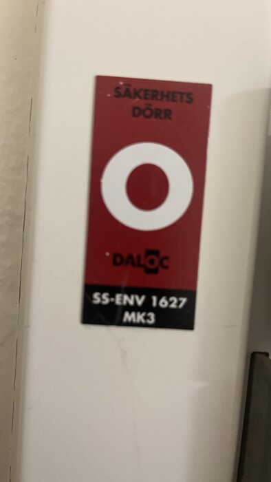 Röd och vit skylt på en säkerhetsdörr från Daloc med märkningen SS-ENV 1627 MK3.