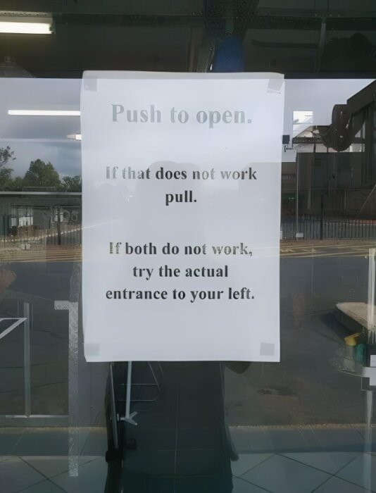 Skylt på en glasdörr med texten: "Push to open. If that does not work pull. If both do not work, try the actual entrance to your left.