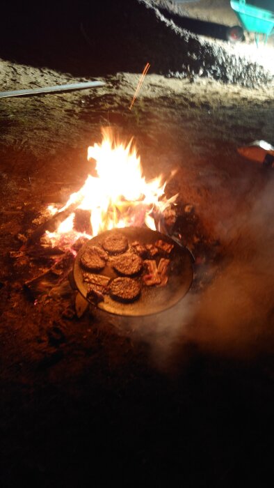 Grillning utomhus med hamburgare och bacon på en öppen eld under en byggfest.