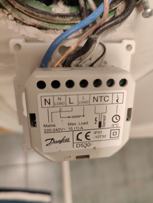 Bild av en Danfoss termostatinstallation med synliga elkablar och märkningar för anslutningar och belastning.