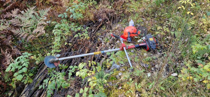 En röjsåg med hjälm och oljeflaska vilar på marken i en skog under en vätskepaus.