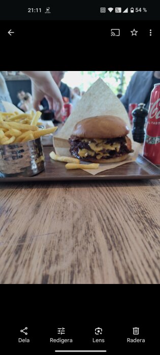 Hamburgare med ost och pommes frites serverade på en bricka, en Coca-Cola burk syns i bild, Rekas restaurang i Lund.