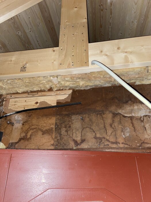 Isolerad luftspalt under takstolar med borrade hål i råsponten och synligt träplank. Fråga om ventilationsbehov och risk för kondens vid tillbyggnad.