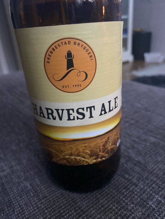 Flaska med Harvest Ale från Grebbestad Bryggeri, etiketten visar en fyr och texten "Grebbestad Bryggeri Est. 1995" i orange topp och "Harvest Ale" i svart nedanför.