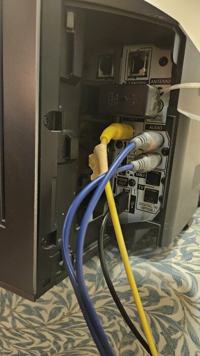Baksidan av en Blu-ray-spelare med flera RCA- och HDMI-kablar anslutna till olika portar för ljud- och videoinmatning och -utmatning.