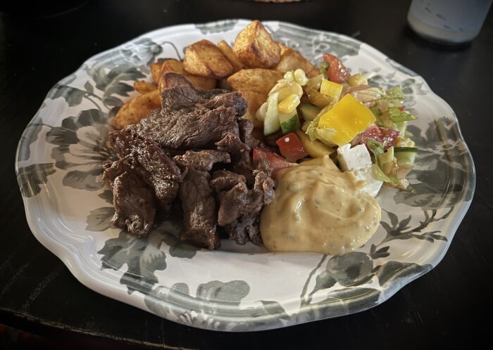 En tallrik med stekt entrecote, ugnsrostad potatis, sallad med tomat och paprika samt en klick bearnaisesås.