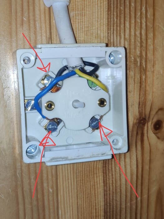 Bild som visar baksidan av en ljusströmbrytare med flera anslutna kablar. Fyra röda pilar pekar mot olika skruvanslutningar för kablarna.
