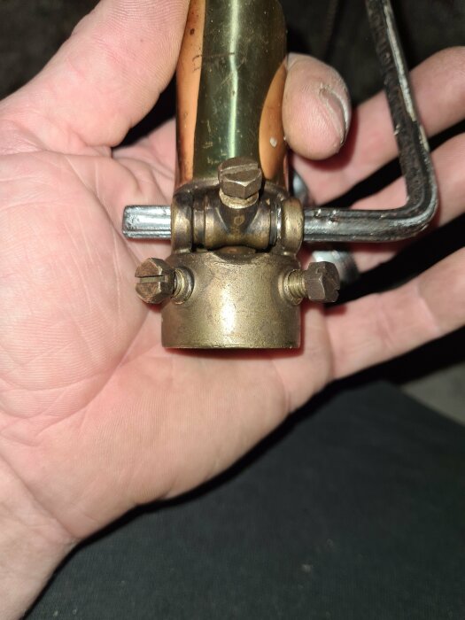 Hand holding a brass draft regulator with two screws and a small lever mechanism; text "kosmos" is partially visible. Query about the manufacturer on a forum.