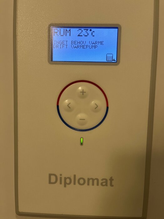 Displayen på en värmepump, märkt "Diplomat", visar att rumstemperaturen är inställd på 23 grader och anger "INGET BEHOV VÄRME".