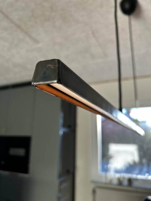 Industriell lampa i svart U-profil med aluminiumprofil och ledstrip monterad i tak, med koppartejp inuti för stilmässig matchning till andra lampor.