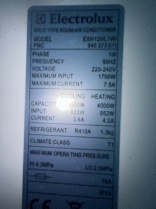 Informationsetikett på en dammig Electrolux luftkonditionering med modellnummer EXH12HL (1W) och tekniska specifikationer såsom spänning, kapacitet och kylmedel.