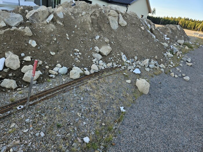 Hög med fyllnadsmassor och stora stenar som skänkes bort, ligger vid kanten av en grusväg i Gemla, Växjö Kommun.