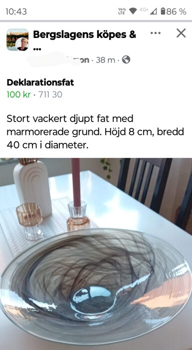 Stort djupt fat med marmorerad grund, omgiven av ljusstakar och vaser på ett bord.