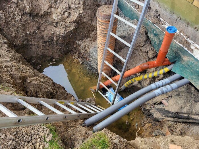 Grav där nya rör och slangar för avlopp och köldbärare har installerats samt en stege som används för att komma ner i gropen.