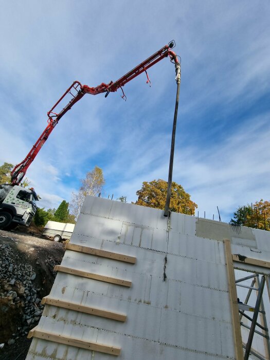 Filade väggar av en källare med en betongbil i bakgrunden och en betongpump som sträcker sig över himlen.