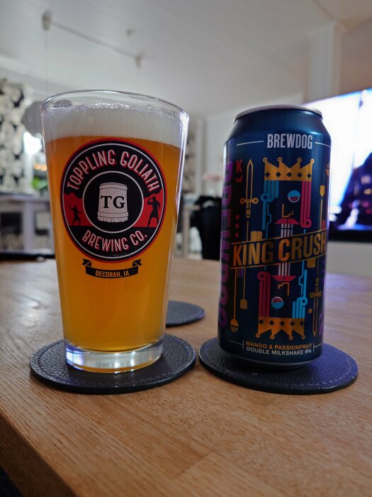 Ett glas öl från Toppling Goliath Brewing Co. och en burk Brewdog King Crush Mango & Passionfruit Double Milkshake IPA, på ett bord i ett vardagsrum.