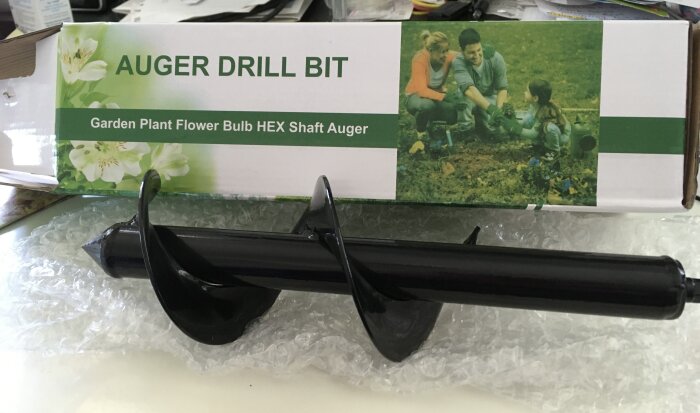 Förpackning med texten "Auger Drill Bit och Garden Plant Flower Bulb HEX Shaft Auger" samt en tillhörande svart borrbit ovanpå bubbelplast.