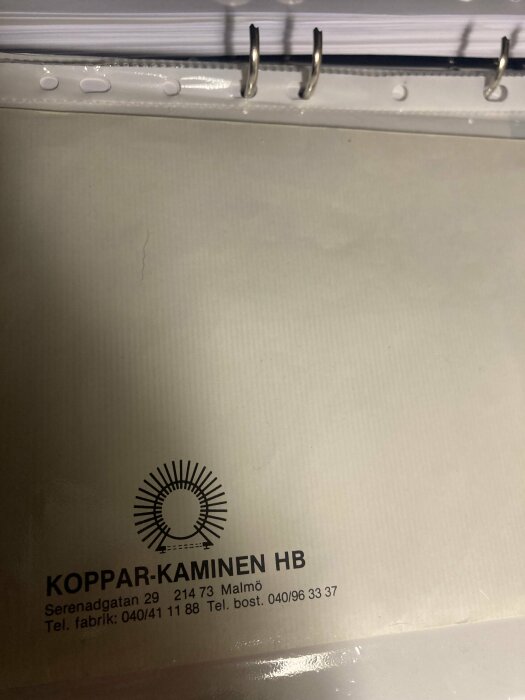 Koppar-kaminen HB" dokument i pärm med kontaktinformation och logotyp. Texten visar adressen Serenadgatan 29, 214 73 Malmö, samt telefonnummer.