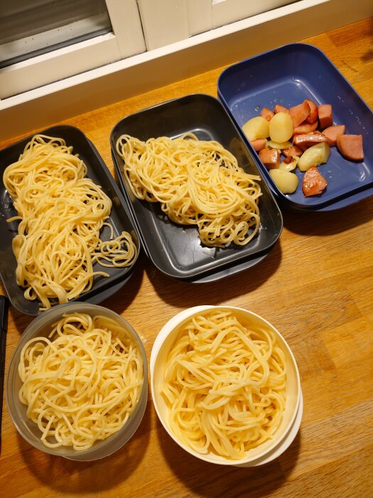 Rester av spagetti och falukorv med potatis i olika skålar på ett bord, saknar sweet chilisås enligt inläggets text.