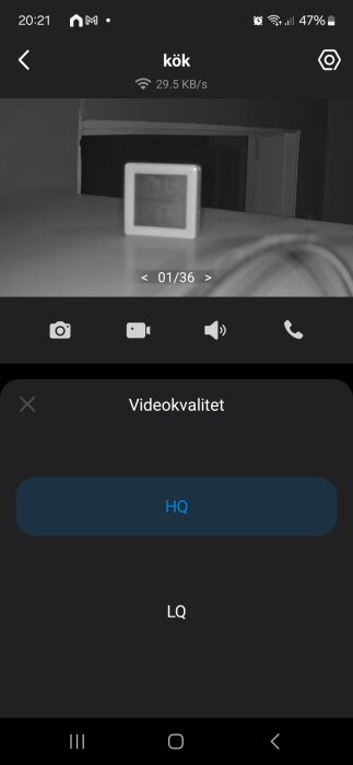 Kameraövervakningsbild från köket visar en termometer på ett bord med en skärm som visar livevideokvalitet och videoläge (HQ eller LQ).